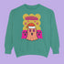 A holiday sweatshirt featuring a cute ghost character wearing a Santa hat, with two smaller ghosts on either side. Above them is the playful text "Boo Humbug," surrounded by snowflakes and festive elements. The design humorously combines spooky and festive themes for a unique holiday look.